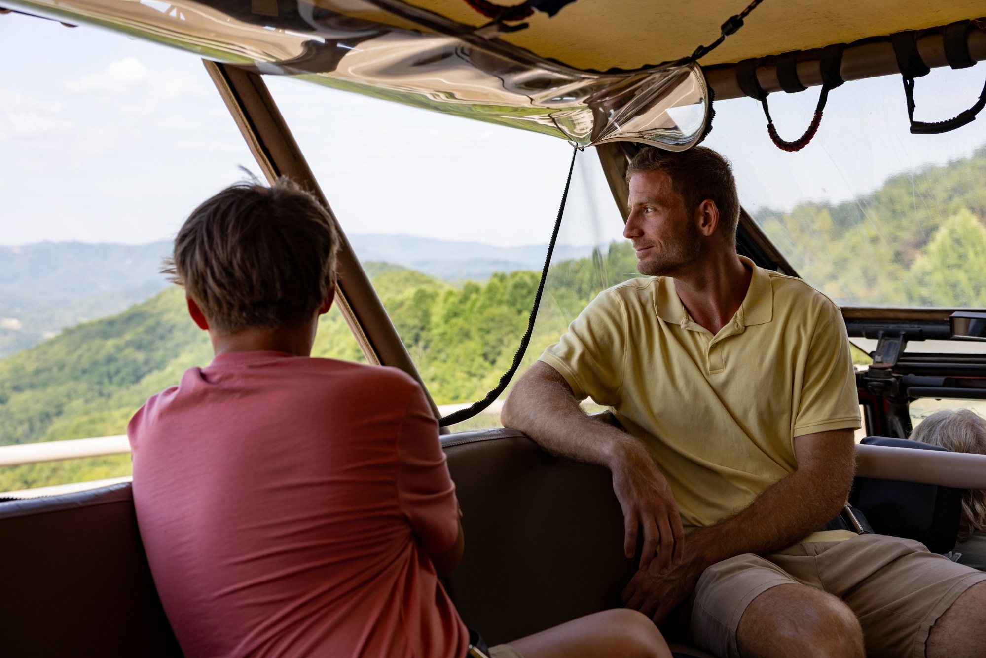 Smokey Mountain Jeep Tours, Summer Two people in a vehicle looking out at a scenic mountain view.