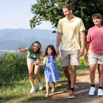 Family of four walking on a trail with mountains in the background.
