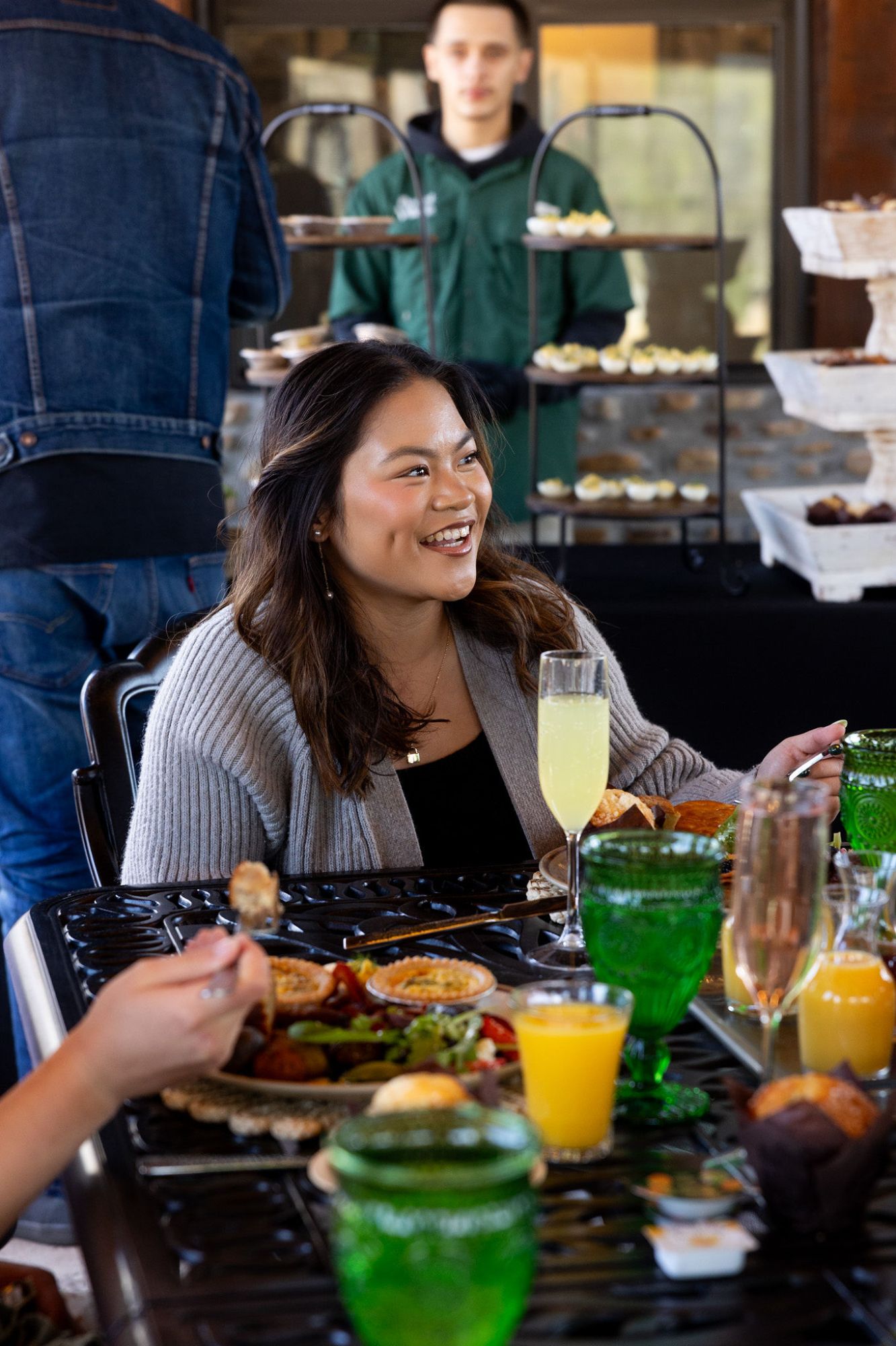 Woman smiling at a table with drinks and food, server in background. Ancient Lore Village Scenic Tour and Lunch with Smoky Mountains Jeep Tours.